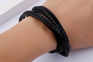 Macro shot of men's multi-layer black braided leather wristband with punk style texture