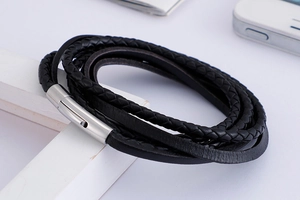 Detail view of multi-layer black braided leather bracelet with silver magnetic buckle