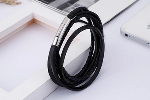 Detail of layered black braided leather bracelet with a polished silver magnetic clasp