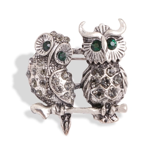 Vintage silver owl brooch with grey and green rhinestones on a white background