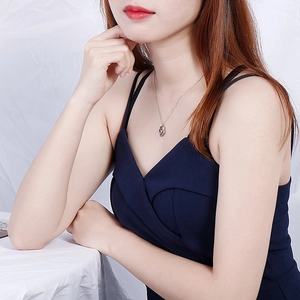 Elegant silver heart pendant necklace on minimalist cross chain worn by female model