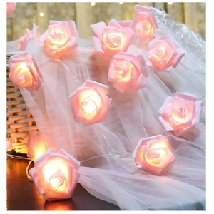 Close-up of pink rose flower LED string lights with warm glow on white gauze decor