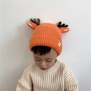Close-up of bright orange knit baby hat featuring cute brown reindeer antlers and ears