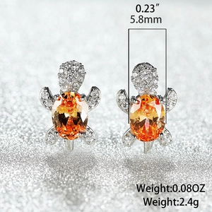Macro shot of sea turtle stud earrings with orange zircon stones and white diamond accents