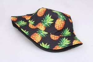 Détail de l'imprimé d'ananas sur le tissu noir d'un chapeau bob réversible en coton