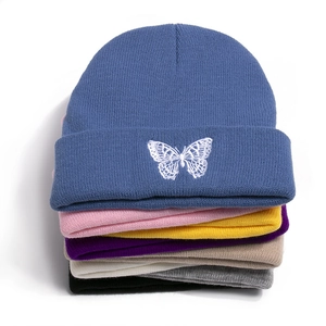 Detailed stack of ribbed knit beanies with butterfly embroidery in multiple colors