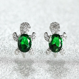 Detail of silver turtle earrings featuring green gemstone and white zircon setting