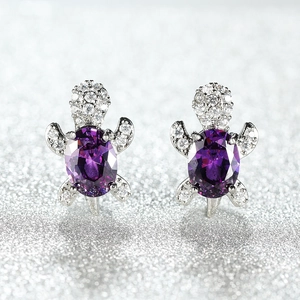Macro detail of silver turtle earrings with oval purple stones and sparkling white zircons