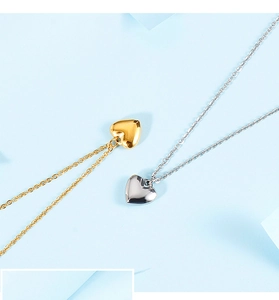 Detailed view of gold and silver heart pendants on delicate cross chains over blue background