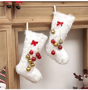 Close-up of white faux fur Christmas stockings with red bows and festive ornaments