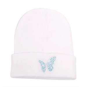 Close-up of white knit beanie featuring delicate light blue butterfly embroidery detail