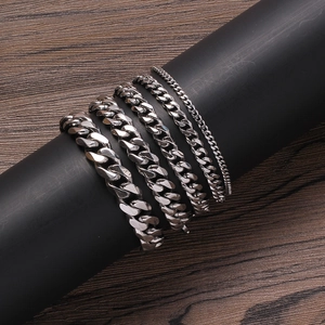 Multiple silver stainless steel Cuban link bracelets in various widths on black display