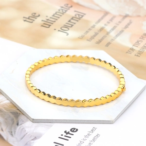 Detailed shot of golden hexagonal geometric bangle with polished honeycomb texture