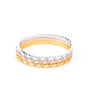 Close-up of hexagonal honeycomb bangle stack with micro-set diamonds in gold and silver