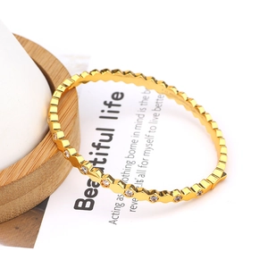 Macro detail of geometric hexagonal gold bangle with micro-set cubic zirconia stones