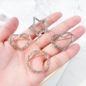 Close-up of four rhinestone brooches in heart, star, and round shapes with gold alloy finish