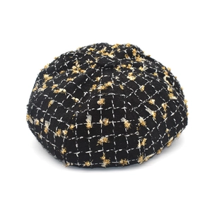 Gros plan sur la casquette en tweed noir et blanc avec des accents de fils dorés