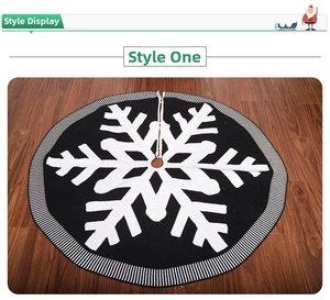 Detailed view of knitted Christmas tree skirt with white snowflake pattern on wood floor