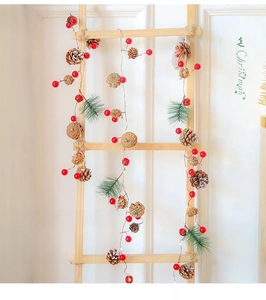 Close-up of LED copper wire lights with pine cones, red berries, and pine needles decor