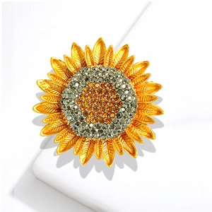Elegant gold sunflower brooch featuring sparkling brown rhinestones on a white podium