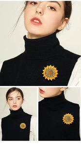 Detailed close-up of a sunflower brooch with yellow petals and sparkling crystals on fabric