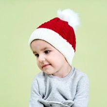 Close-up of kids red and white knitted hat with pompom and soft textured weave