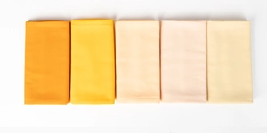 Detail showing five gradient yellow pearl chiffon hijabs neatly folded in a row