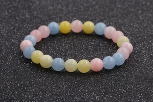 Macro shot of colorful pastel morganite beads on a sparkling dark background