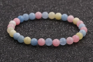 Detailed top view of a pastel morganite beaded bracelet set on a black glitter background