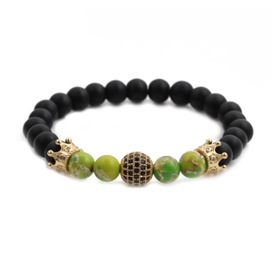 Detail of beaded bracelet with black matte beads, gold crowns and green marble accents