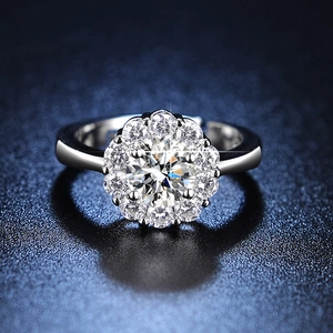 Macro shot of silver six-prong moissanite ring with floral halo on dark blue background