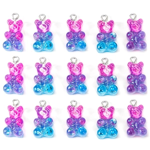 Macro shot of 15 gradient glitter resin gummy bear pendants with metal ring connectors