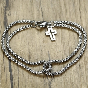 Close-up of a silver double-layered stainless steel chain bracelet with a cross charm