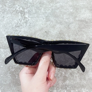 Oversized black square sunglasses with gold stud embellishments and dark lenses