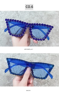 Detailed view of oversized blue sunglasses featuring crystal rhinestones and blue lenses