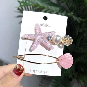 Close-up of pink glitter starfish and shell hair clips with pearls on a display card