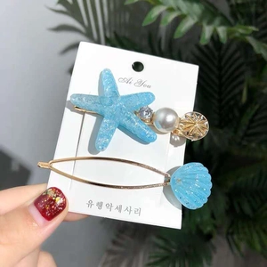 Close-up of glitter blue starfish and shell hair clips with pearls and rhinestones