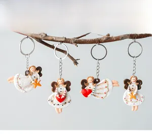 Detailed view of four resin Christmas angel keychains hanging on a decorative branch