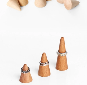 Three metal rings displayed on solid wood cone stands on a clean white background