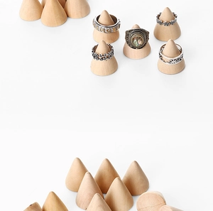 Close-up of conical solid wood ring holders displaying various jewelry pieces on white background