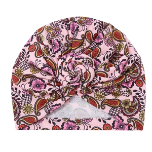 Detail of baby turban hat featuring pink floral paisley pattern and twisted rose knot