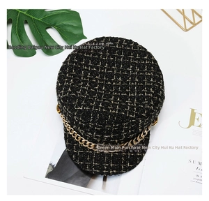 Detail of tweed newsboy cap with gold chain and black and gold plaid texture