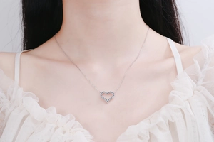 Detail of S925 sterling silver heart pendant necklace on model with white lace shirt