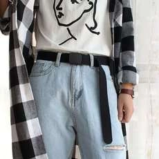 Detail of a thin black canvas belt worn on light blue jeans for a casual street style look