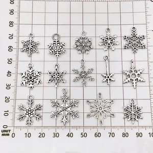 Silver snowflake charms in various sizes measured on a mm scale background for DIY jewelry