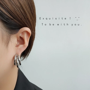 Detail of silver triple-hoop earrings featuring high-polish finish and minimalist style
