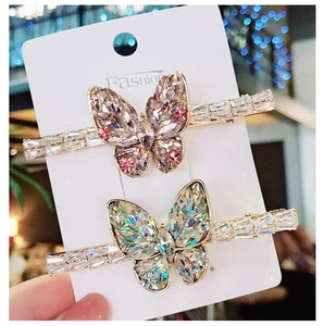 Detailed view of two gold butterfly hair clips with shimmering pink and blue crystals