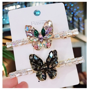 Close-up of gold butterfly hair clips with colorful and black rhinestones on card