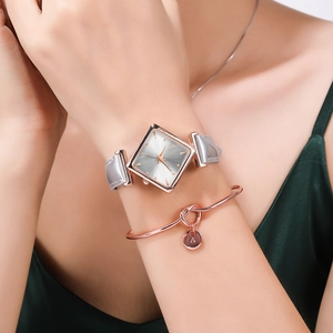 Detail of square rose gold watch with gray leather strap and matching letter A bracelet