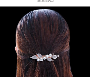 Detailed view of a gold leaf hair clip with pearls and rhinestones on hair